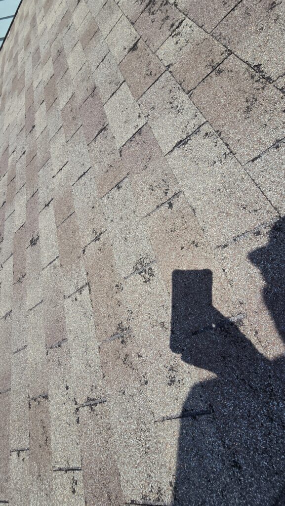 man taking photo of hail damage on roof